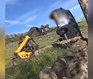 Un granjero arrastra un coche con su tractor.