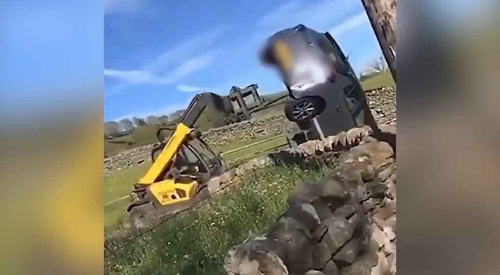 Un granjero arrastra un coche con su tractor.