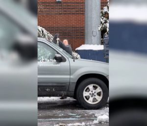 Mujer trata de quitar el hielo de su coche