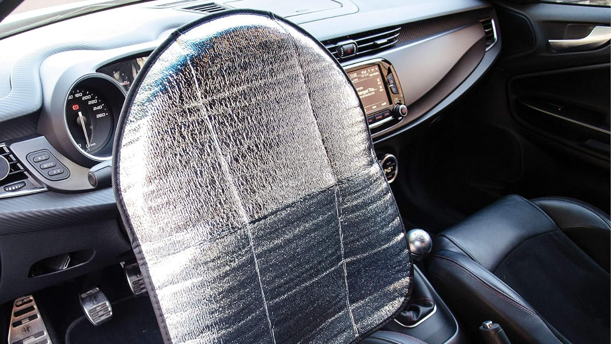 Un parasol que cubre el volante en el interior de un coche.