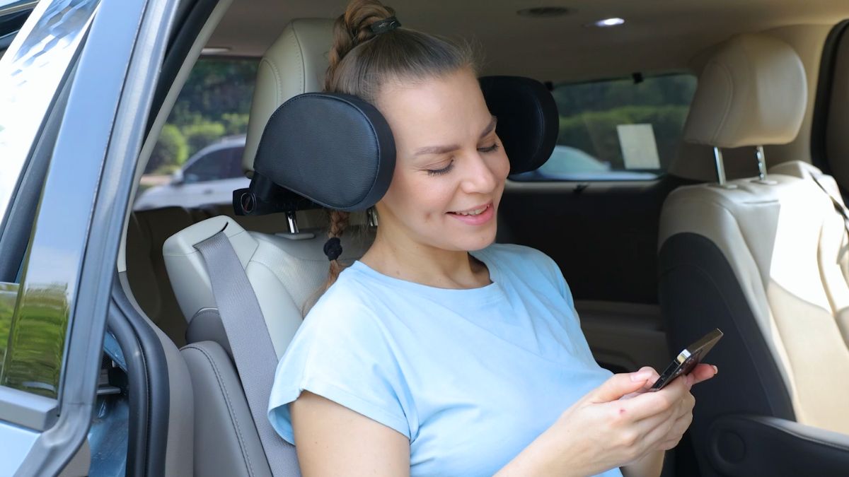 Una mujer utilizando el reposacabezas ajustable del coche.