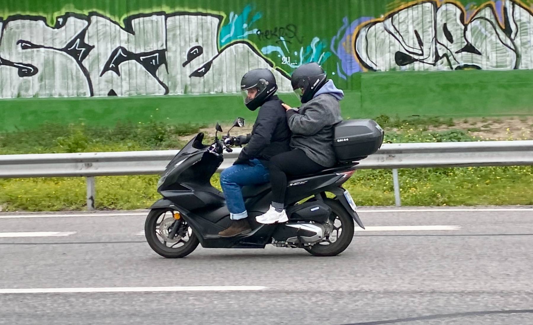Pasajero de una moto utilizando el móvil