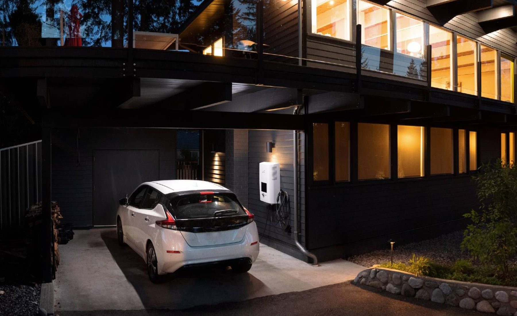 Coche eléctrico cargando en casa por la noche.